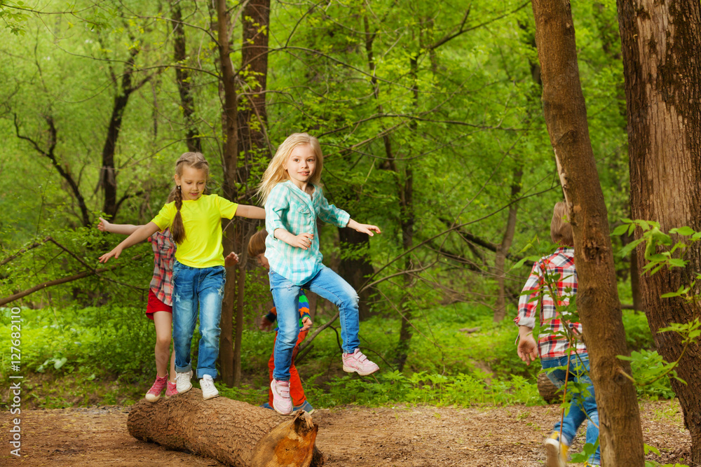 快乐的孩子们站在森林里的原木上保持平衡