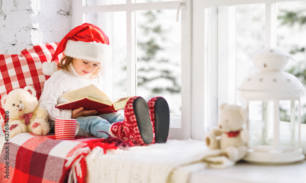 快乐的孩子坐在冬窗边看书
