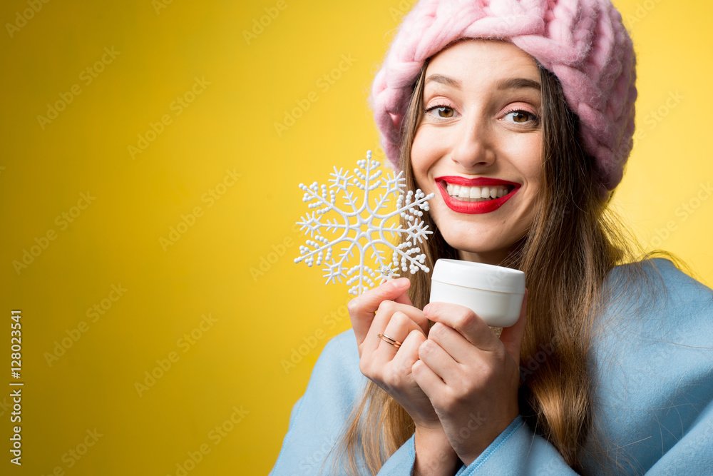 一位美丽女人的彩色冬季肖像，黄色背景上有面霜和雪花