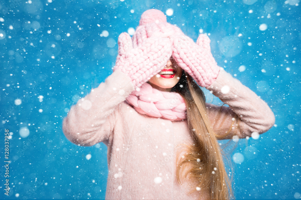 一位美丽女人的冬季肖像，她戴着针织手套，站在蓝色的背上
