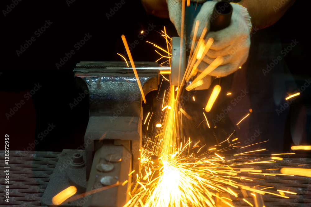 工人用研磨机切割，并用许多尖锐的火花焊接金属。
