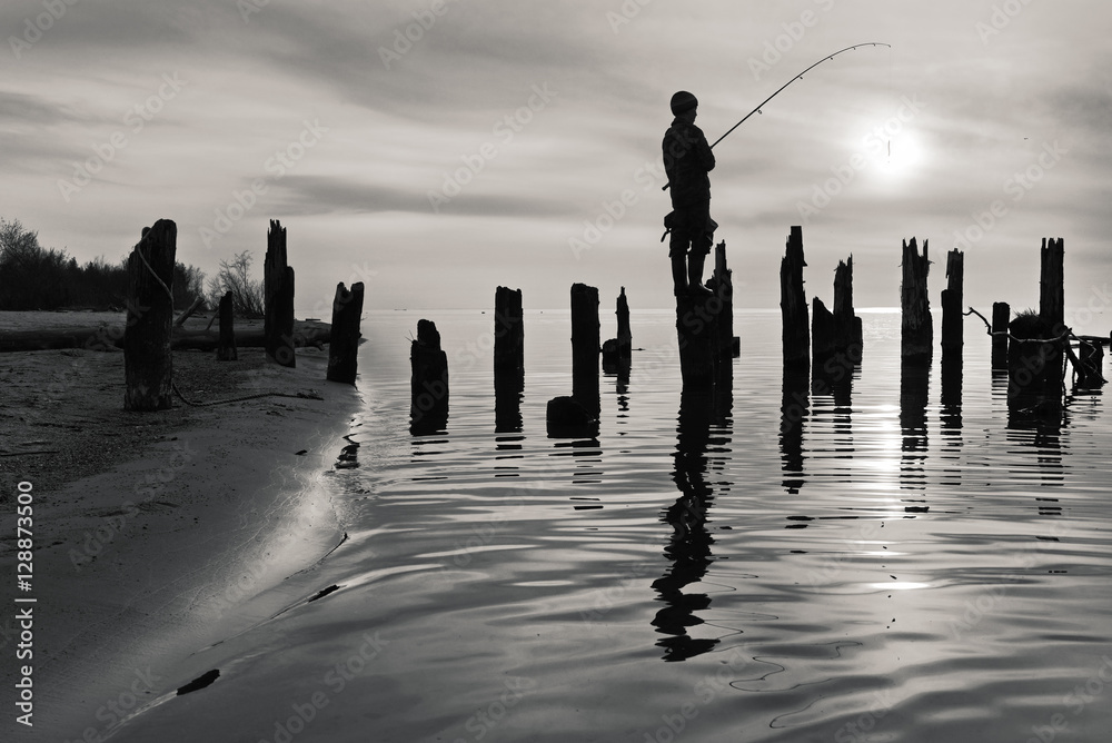 渔夫站在旧原木码头上的黑白照片。
