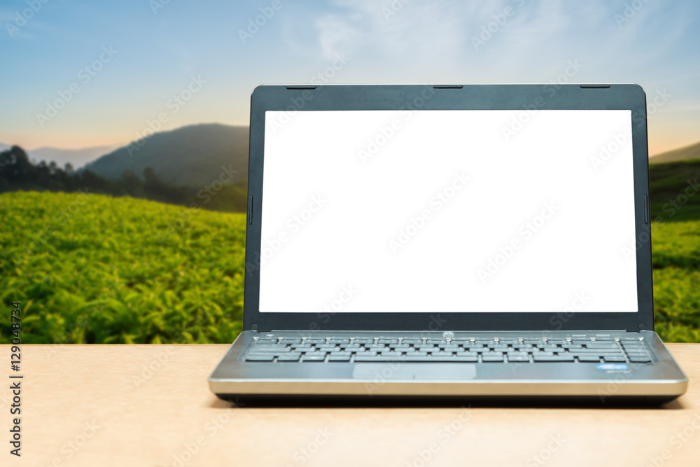 桌子上有空白屏幕的笔记本电脑，背面是模糊的绿色