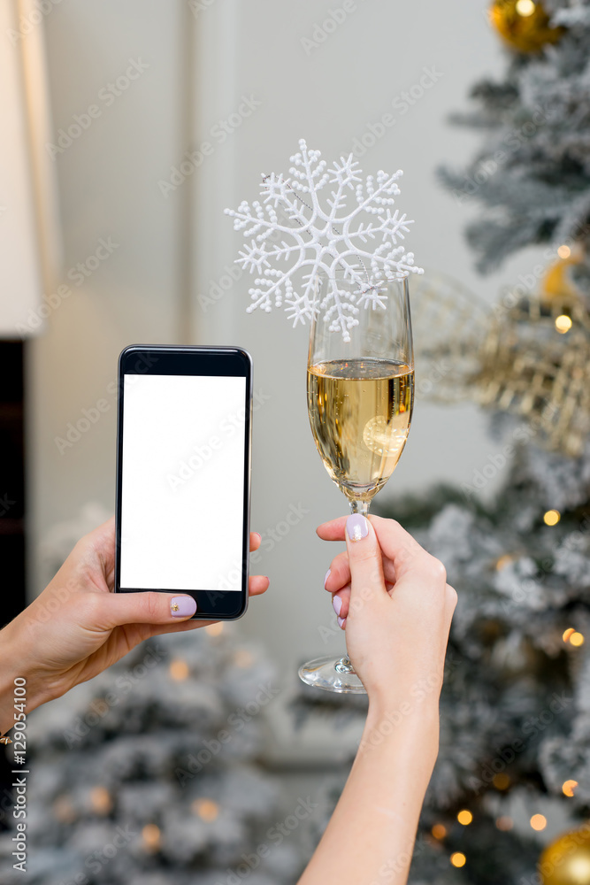 圣诞节拿着一杯雪花起泡酒和空屏智能手机