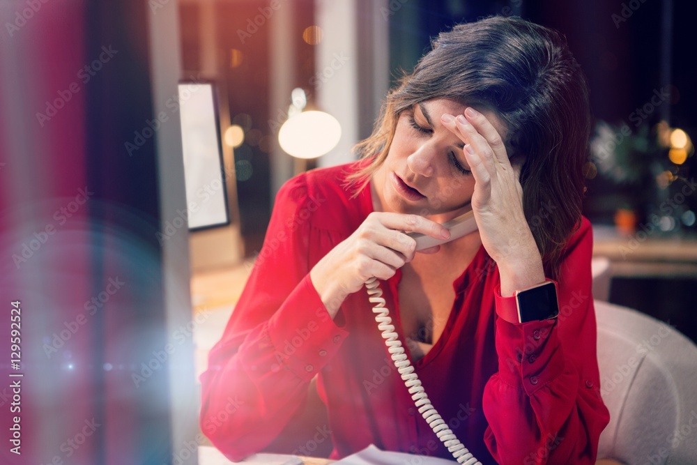 Stressed businesswoman talking on phone at desk