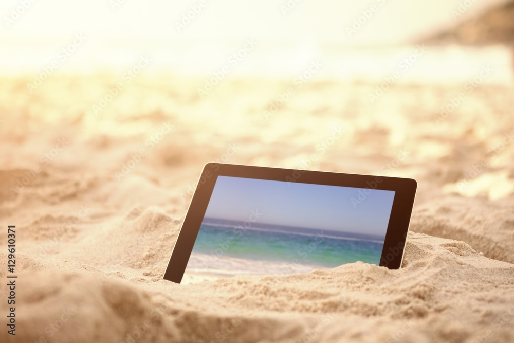海滩沙滩上保存的数字平板电脑的合成图像