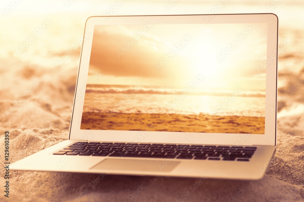 Composite image of laptop kept on sand