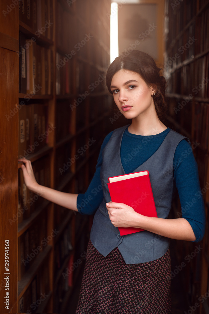年轻女孩站在书架之间