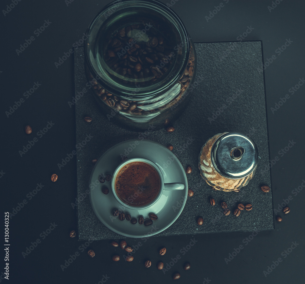 Cappuccino. Concept. Glass jar with coffee beans and brown sugar cane on a dark background. Retro. V