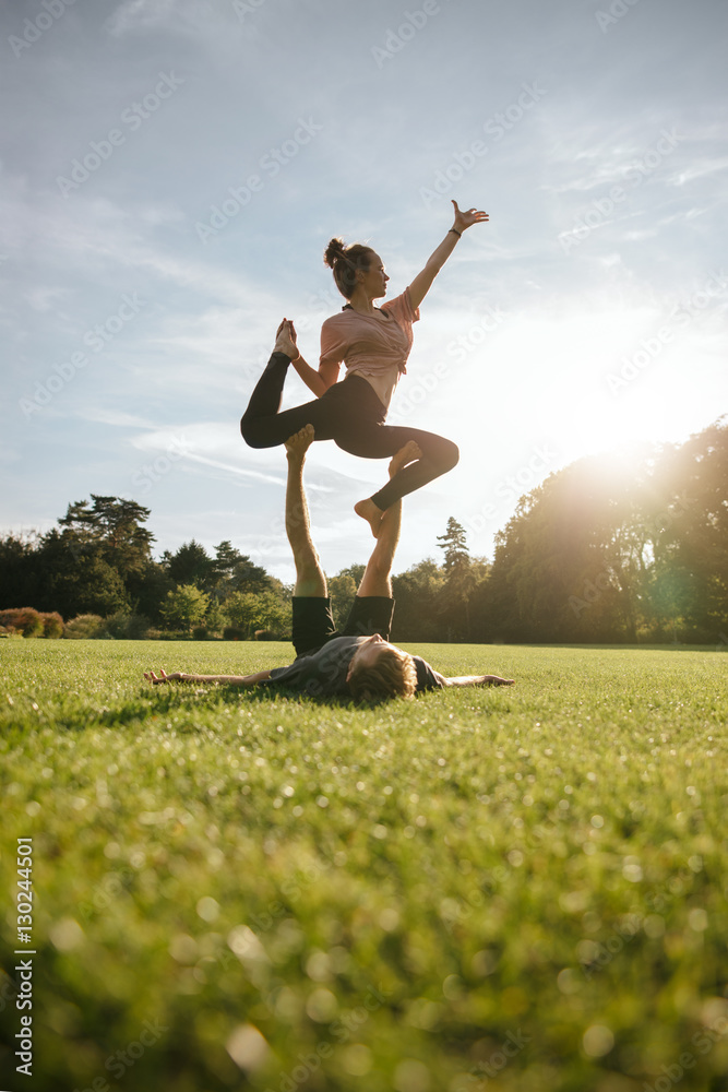 Healthy young couple doing acrobatic yoga