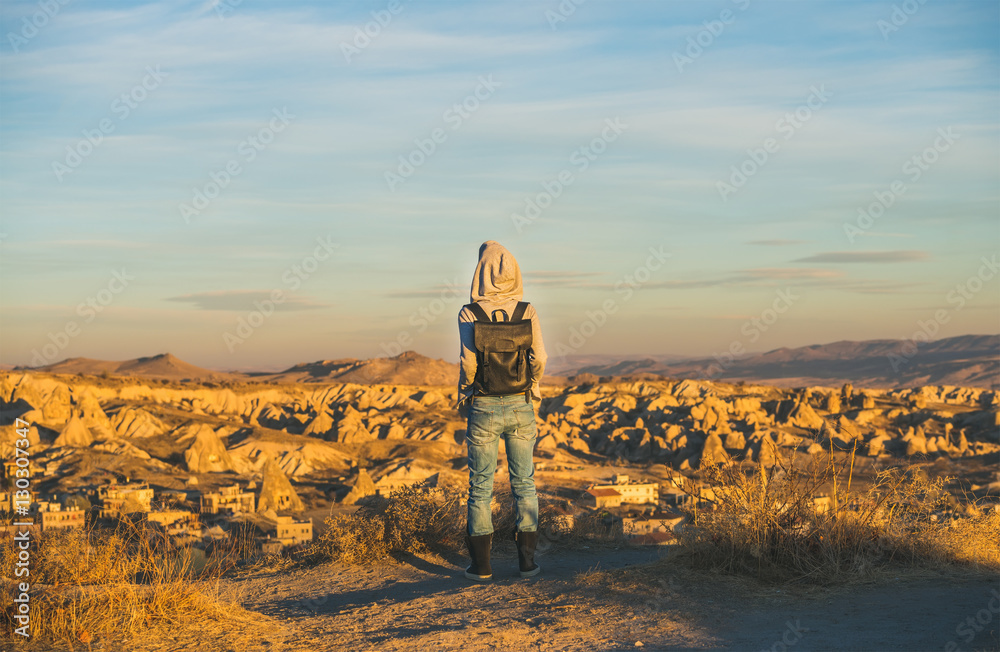 穿着连帽衫、背包和牛仔裤的年轻女性旅行者站在山上看日出