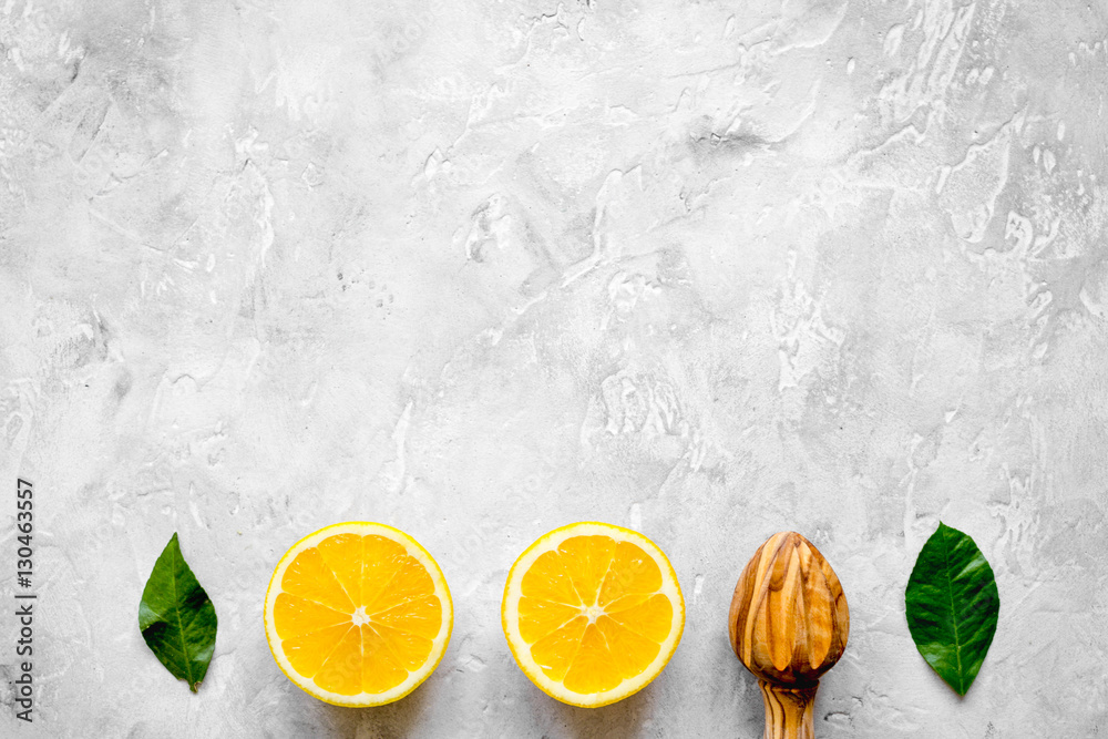 cut oranges and wooden juicer on concrete background top view