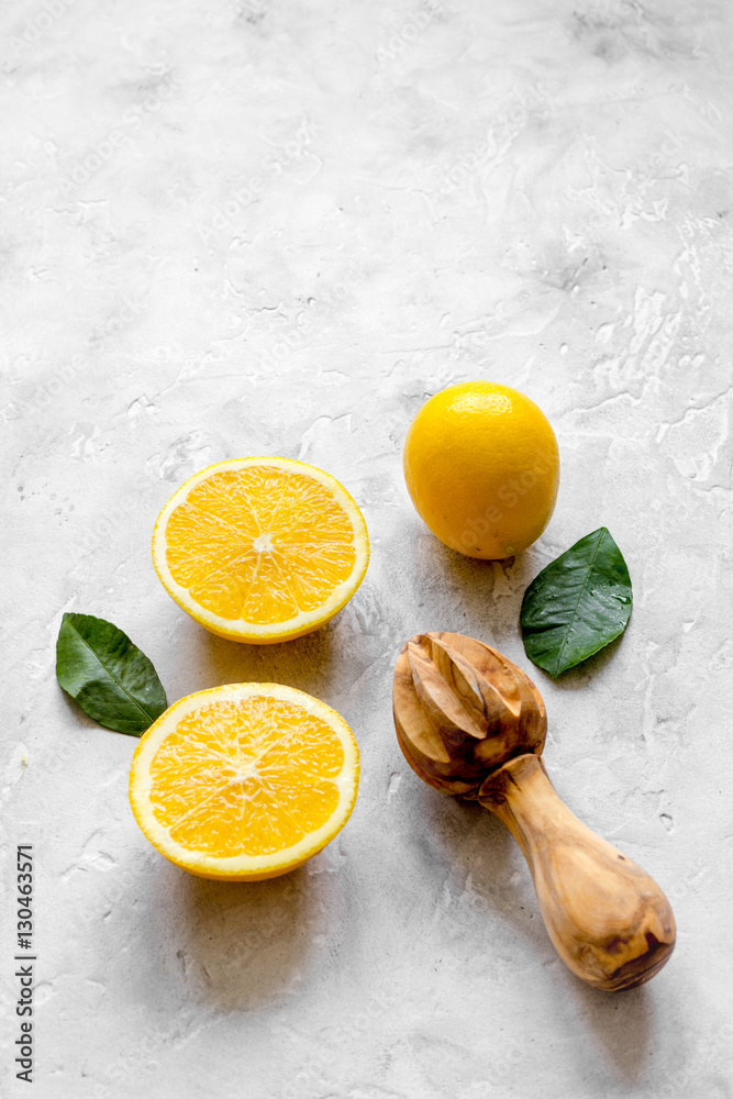 cut oranges and wooden juicer on concrete background top view