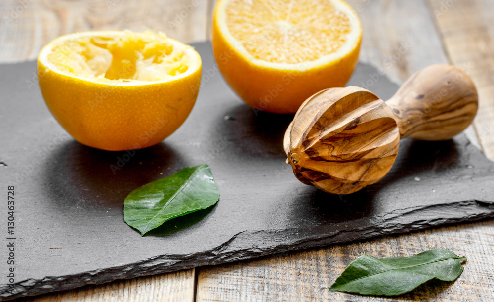 cut oranges in half and juicer on wooden background