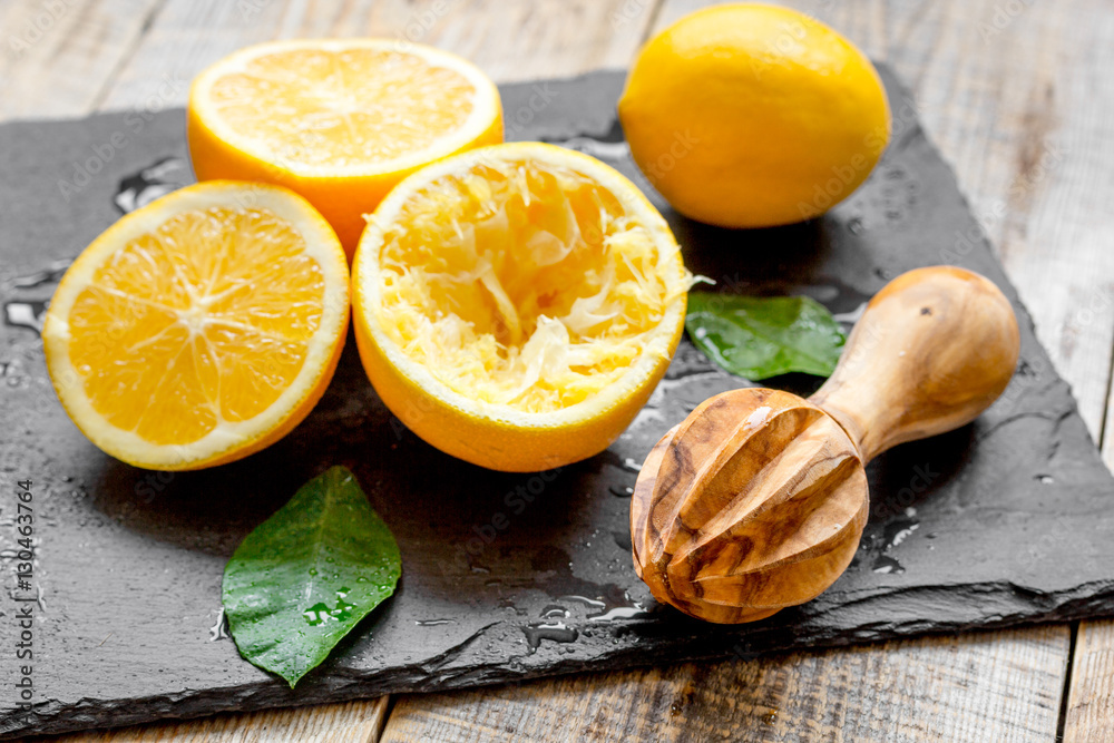 cut oranges in half and juicer on wooden background