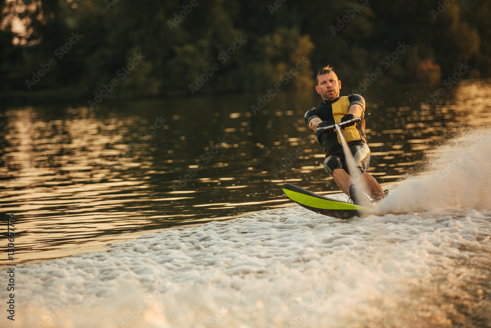 Man riding wakeboard on wave of motorboat