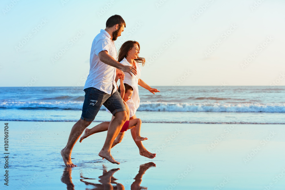 幸福的家庭——父亲、母亲、小儿子手牵着手，一起在水池边溅水奔跑
