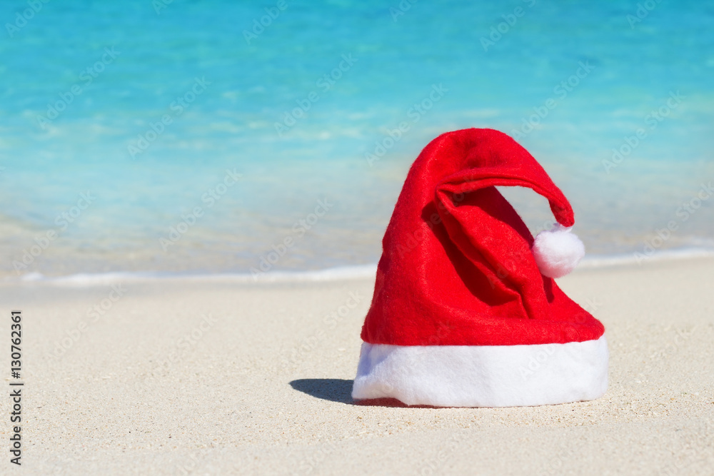 圣诞老人的红帽子，背景是海滩和蓝色海洋