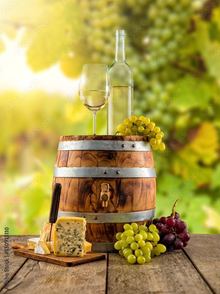 White wine served on wooden barrel, vineyard on background