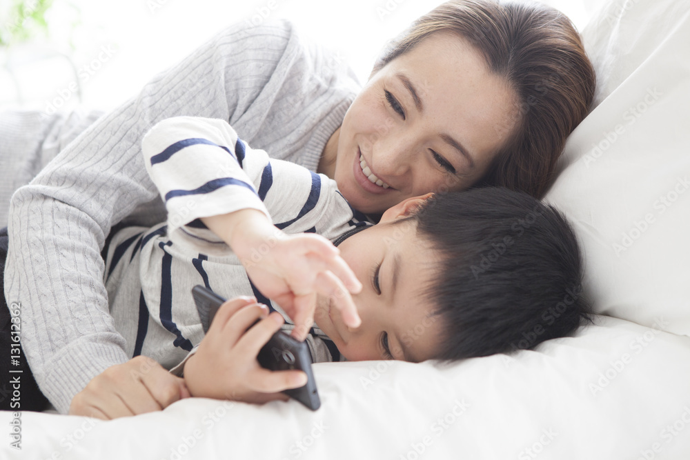 Mother and son are watching smartphone in bedroom