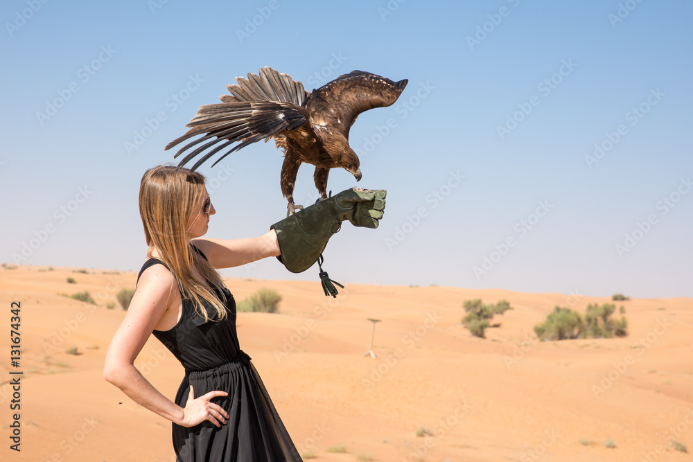 大斑鹰（Clanga Clanga）与一位美丽的年轻女性模特在沙漠猎鹰比赛中