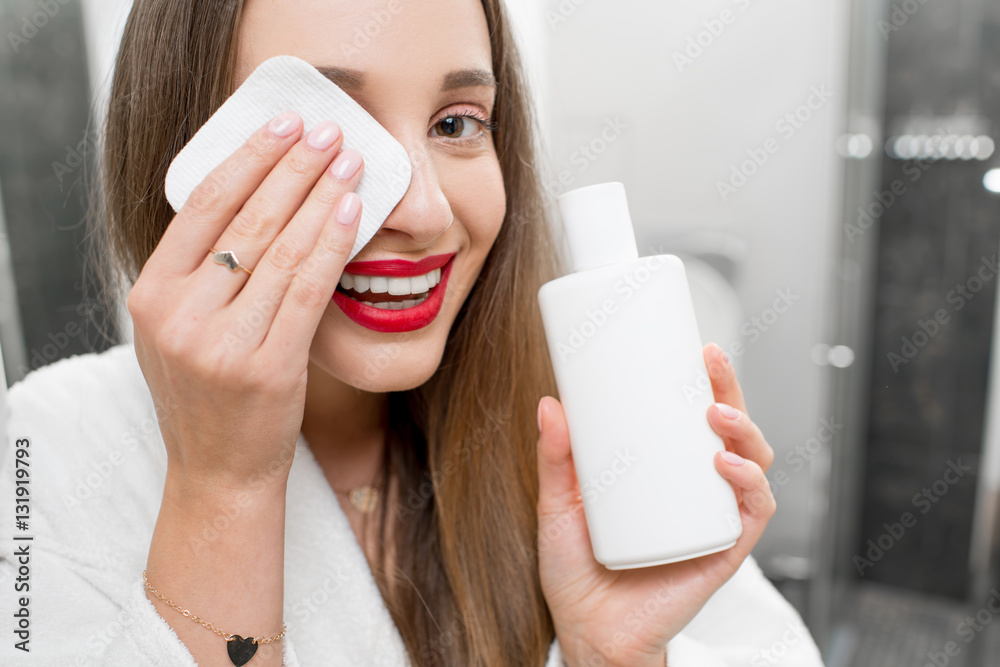 女人在浴室用棉签卸妆。年轻女孩在护理皮肤