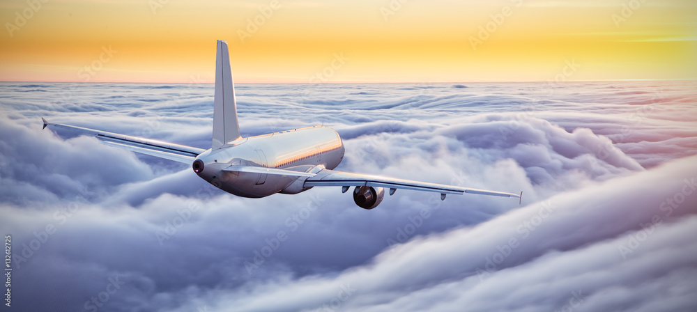 Airplane flying above clouds in dramatic sunset