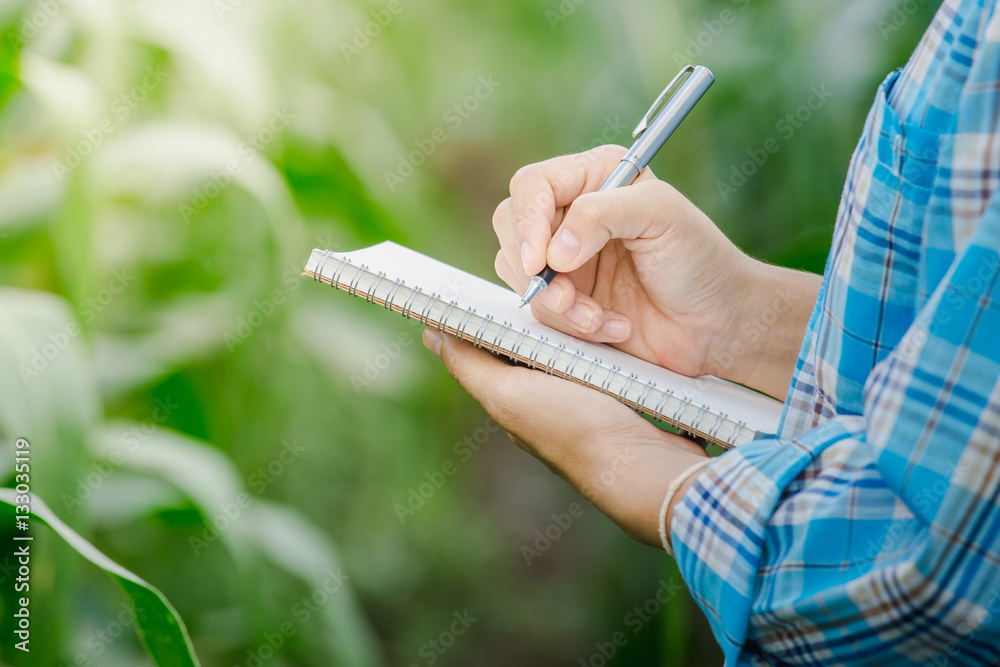 妇女在农业花园里用钢笔在笔记本上手写笔记。