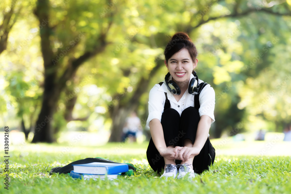 Asian female student girl outside in park listening to music