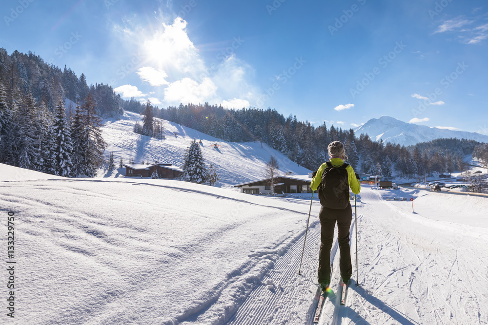 Cross-country skiing in sunny winter landscape, beautiful mountains in background