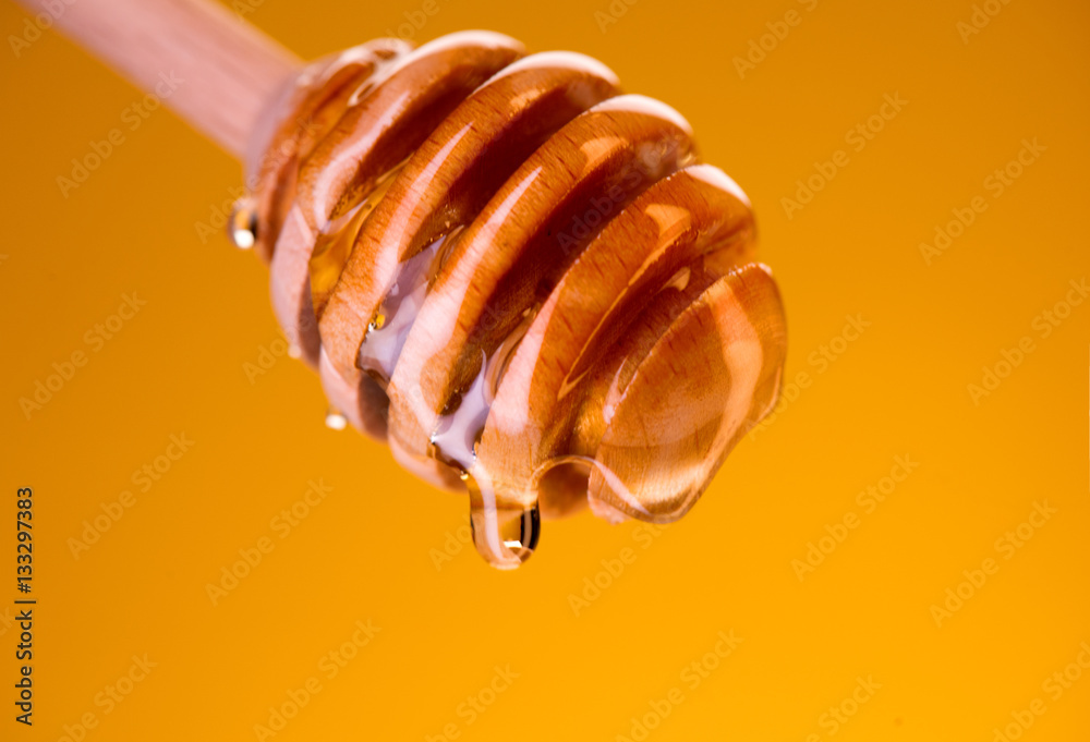 蜂蜜从黄色的蜂蜜勺中滴下。从木制蜂蜜勺中蘸下厚厚的蜂蜜
