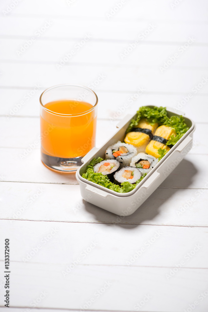 Orange juice and bento box with different food, fresh veggies an