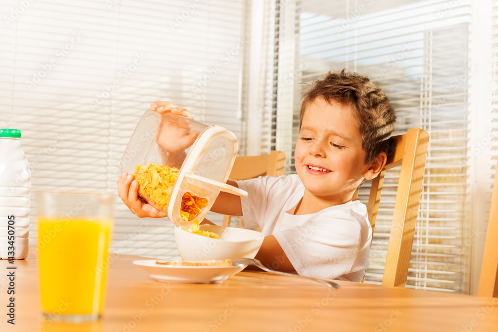 Little boy pouring corn flakes making breakfast