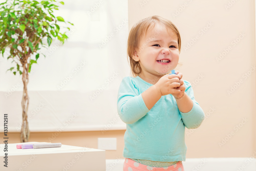 Happy toddler girl playing with chalk