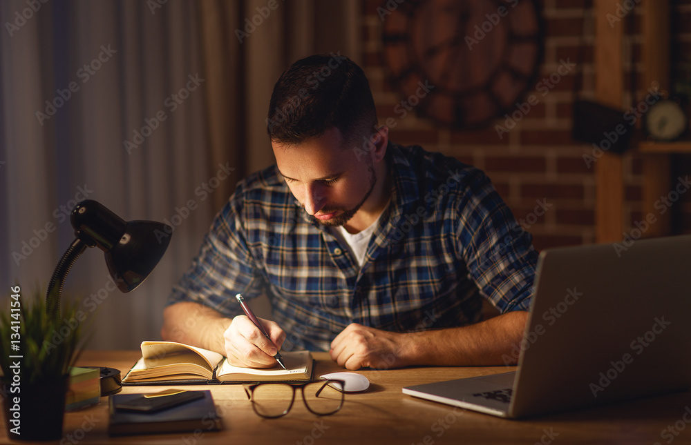 一个晚上在黑暗中在家里用电脑工作的人。