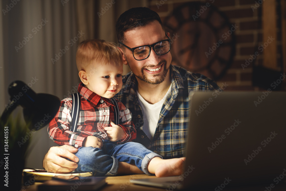 爸爸和儿子宝宝在家里摸黑在电脑前工作。