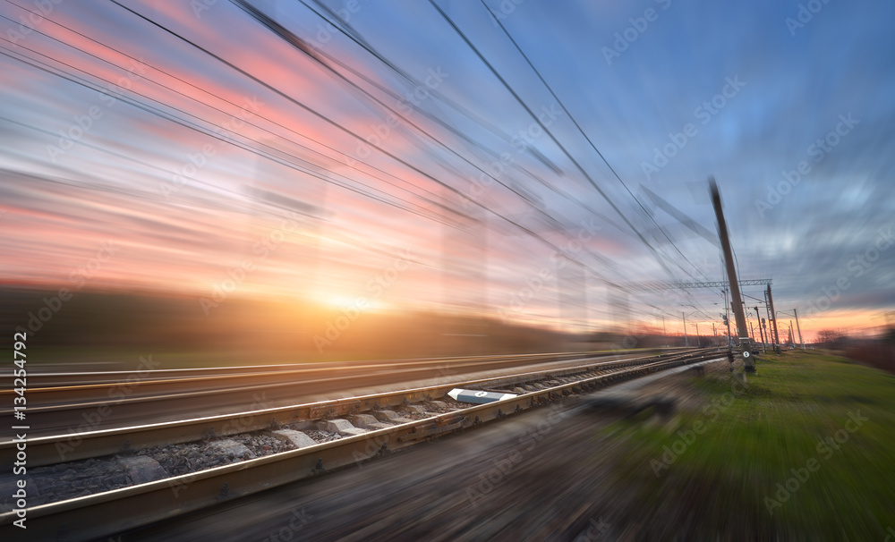 Railroad in motion at sunset. Railway station with motion blur effect against colorful blue sky, Ind