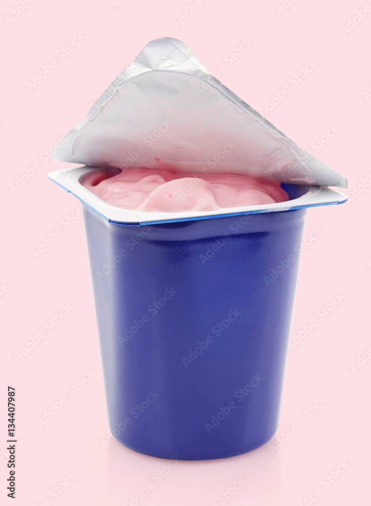 蓝色塑料罐中的新鲜粉红色浆果酸奶