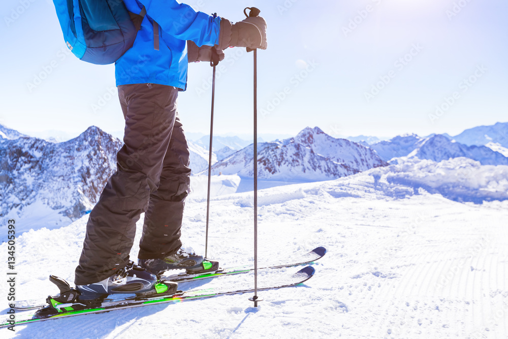 Closeup skier skis on snow, white sunny winter mountain landscape