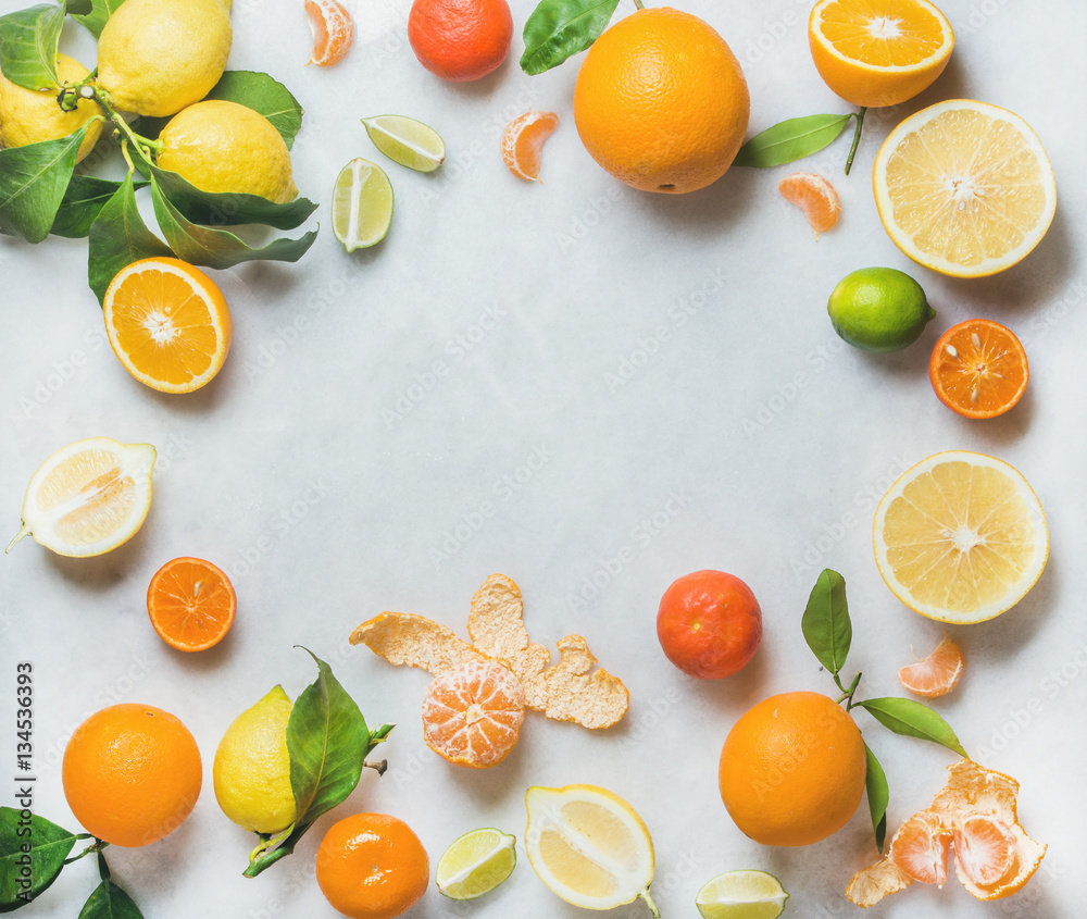 Variety of fresh citrus fruits for making juice or smoothie over light grey marble table background,