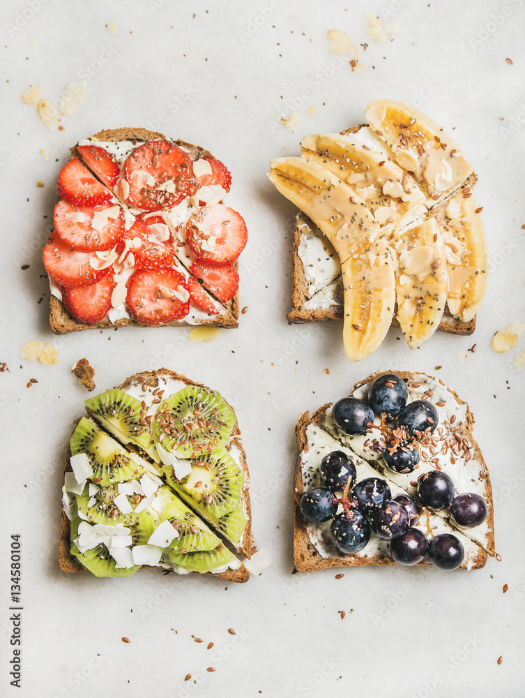 Healthy breakfast toasts. Wholegrain bread slices with cream cheese, various fruit, seeds and nuts. 
