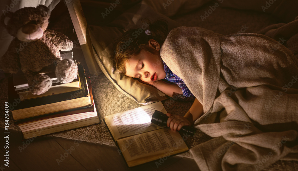 child girl sleeping in tent with  book and flashlight