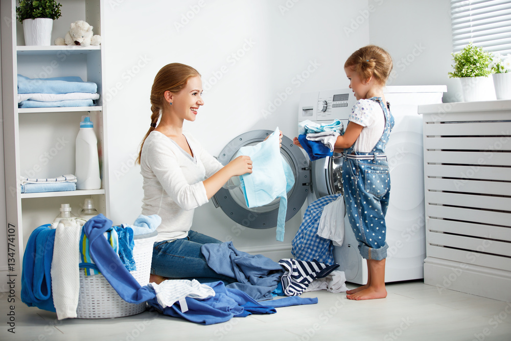 洗衣机附近洗衣房的家庭母亲和女婴