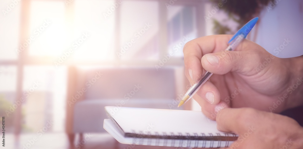 Composite image of close up of man writing in notepad