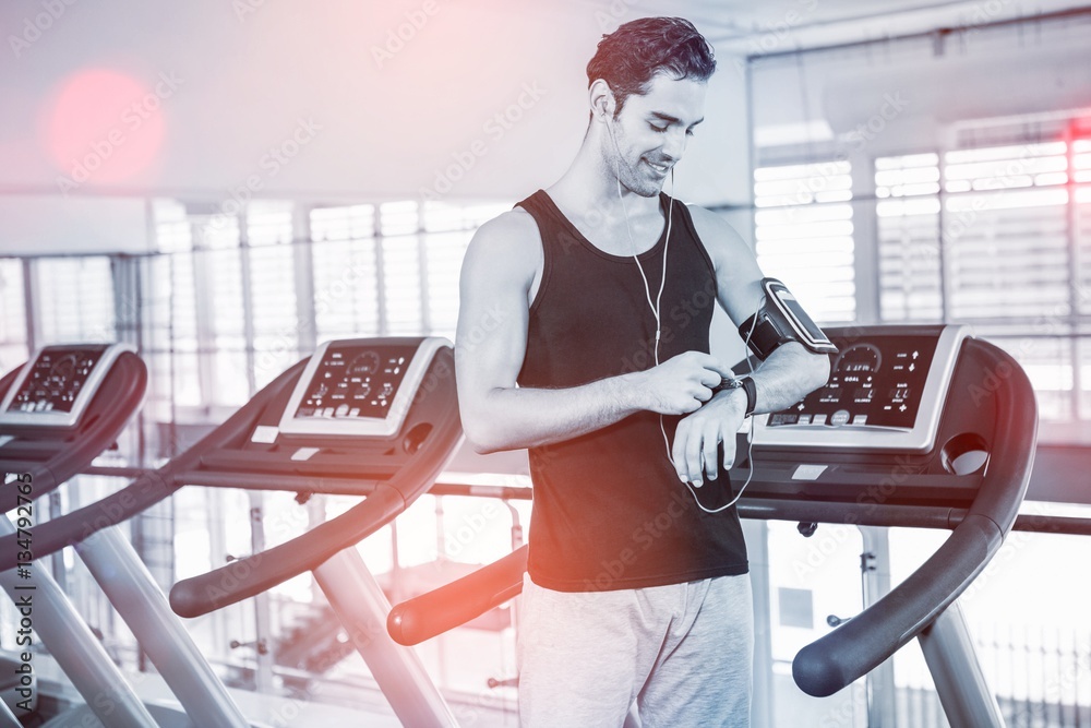 Smiling man on treadmill using smart watch