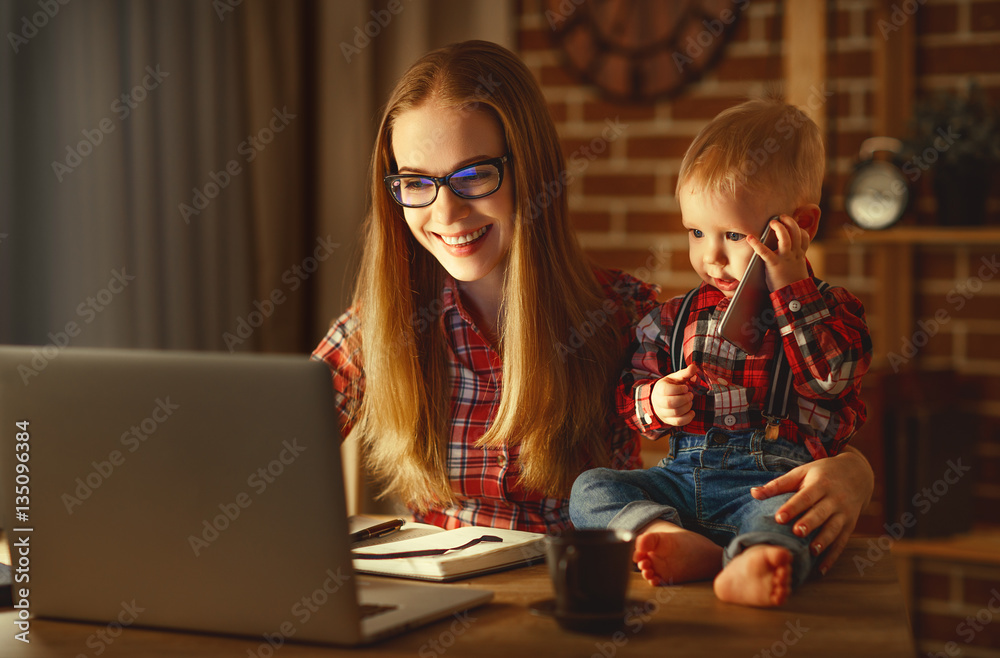 woman mother working  with a baby at home behind a computer
