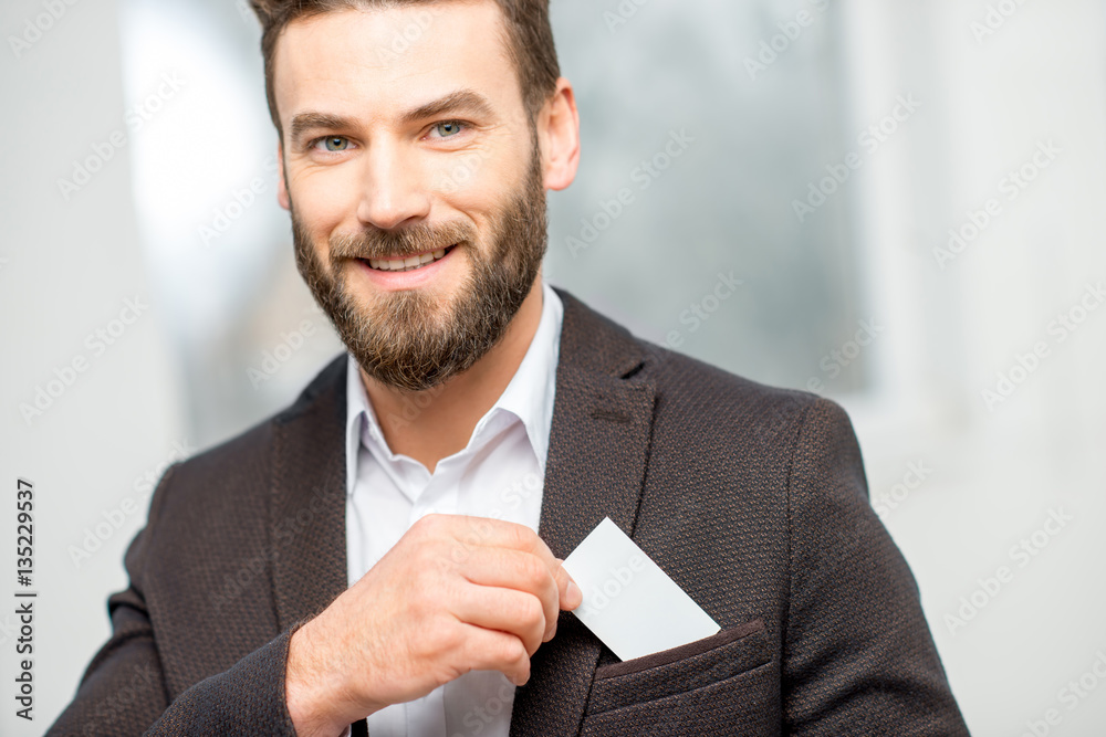 Elegant man in the suit putting business card into the pocket. White card to copy paste
