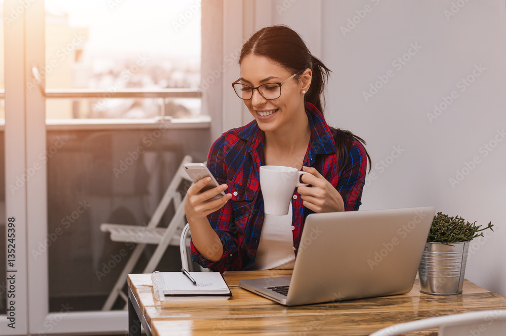 Businesswoman drinking coffee and texting on mobile phone