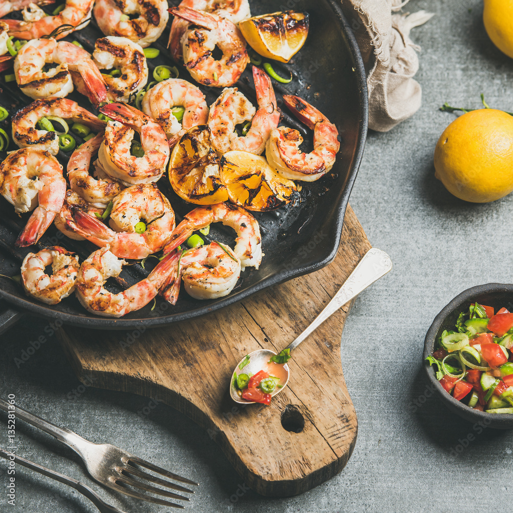Seafood dinner. Close-up grilled tiger prawns in cast iron grilling pan with lemon, leek, chili pepp