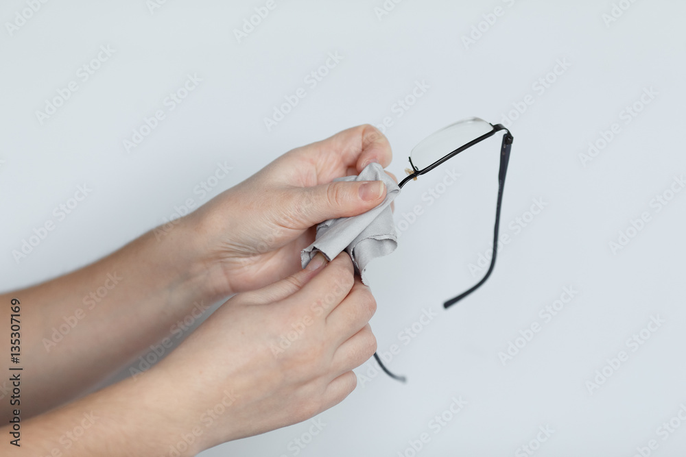 Women hand cleaning glasses lens with isolated background.